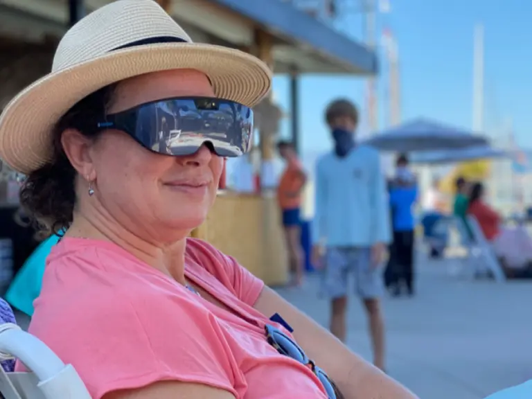 A woman wearing the IrisVision Vista low-vision headset outdoors