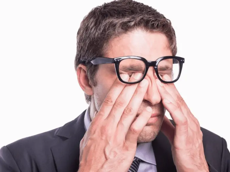 A man rubbing his eyes while recovering after retinal detachment surgery